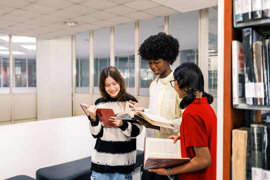 Diverse Students Reading and Discussing Books Together in Library