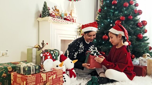 Mother and Daughter Opening Christmas Gift Beside Holiday Tree