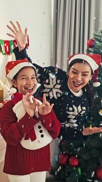 Joyful Mother and Daughter Hugging Snowman at Christmas