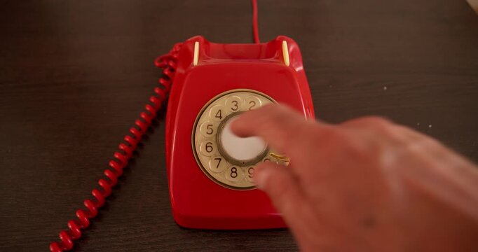 Dialing Back Time: A finger is poised to dial on a classic red rotary telephone, evoking a sense of nostalgia and communication from a bygone era.