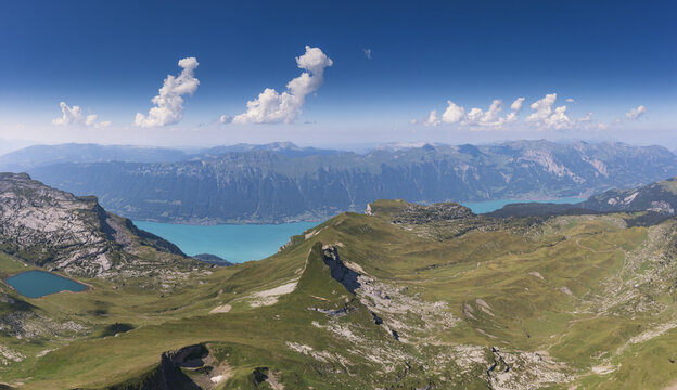 Aerial view of Faulhorn mountain peak with the turquoise waters of Bachalpsee and Lake Brienz, surrounded by lush green alpine slopes in Grindelwald, Canton of Bern, Switzerland.