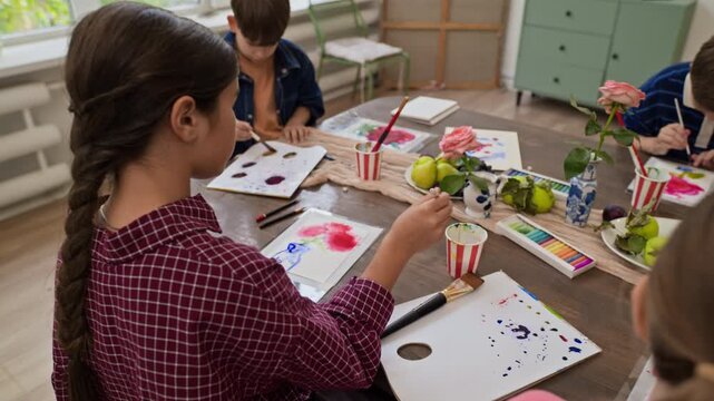 Children painting still life with watercolors during art master class. Footage fits educational campaigns, creative workshop promotions, and school advertising