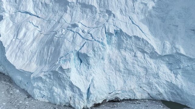 Aerial view of massive glacier surface with deep crevasses and blue ice textures in Ilulissat, Avannaata Municipalit, Greenland.