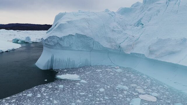 Aerial view of a massive iceberg floating in the icy waters of the Ilulissat Icefjord, surrounded by sea ice fragments in Ilulissat, Avannaata Municipalit, Greenland.