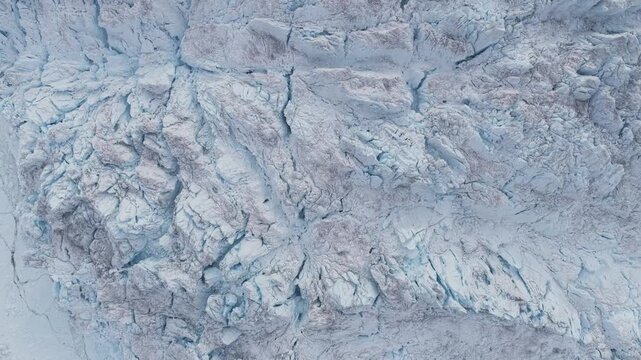Aerial view of the massive, crevassed surface of the Ilulissat Icefjord glacier, showcasing deep blue ice formations and rugged textures in Ilulissat, Avannaata, Greenland.