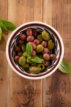 Fresh olives and olive oil on rustic wooden background.