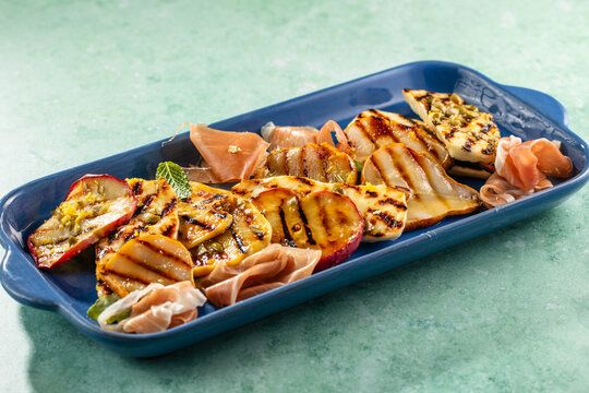 Fresh salad bowl with grilled halloumi cheese and roasted pear and apples, seeds.