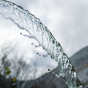 View of a clear stream of water flowing with visible droplets against a cloudy sky in Tafjord, More og Romsdal, Norway.