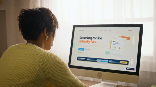 African American teenager browsing online learning platform on desktop computer from rear angle. Clip suitable for distance education advertisements and edtech promotional campaigns