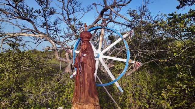 VENEZUELA. Beautiful hand-carved wooden statue of Virgin of Valley (Virgen del Valle), patron saint of sailors and fishermen with rosaries. religious monument with decorative ship steering wheel