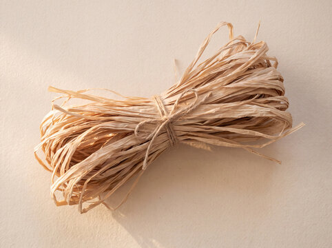 Raffia bundle tied with twine on a cream surface