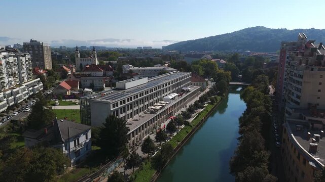 Center Rog overlooks the Ljubljanica River amid Ljubljana rooftops and trees, revealed in a drone pull-back shot.