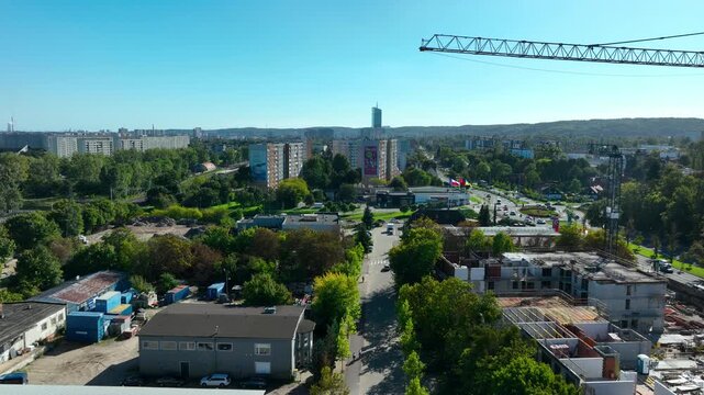High angle drone shot showing a construction site with cranes, residential buildings, and green urban spaces under a clear blue sky. Useful for real estate and urban development projects.