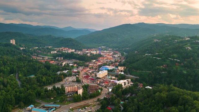 Gatlinburg, Tennessee town tourist area with illuminated streets and dark scenic mountain backdrop after sunset time.