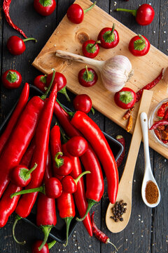 Fresh red hot chili peppers, garlic bulb, black peppercorns and paprika powder on dark rustic wooden table. Organic ingredients for spicy Mexican cooking, Hot spices.
