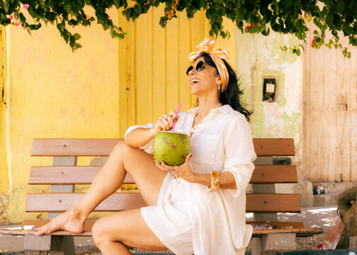 Mature Woman Over 50 Enjoying Coconut Water While Traveling in a Tropical Destination