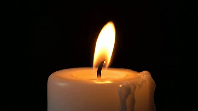 Burning white candle with flickering flame isolated on black background, for relaxation and, memorial