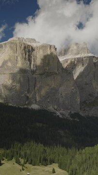 A vertical video aerial view of the Sella towers near the Sella pass with clouds after a storm, Canazei, Italy
