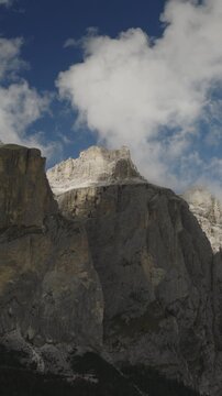 A vertical video aerial view of the Sella towers near the Sella pass with clouds after a storm, Canazei, Italy