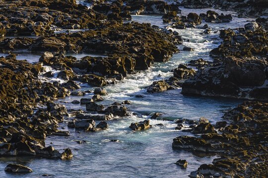 Rushing stream meanders through rocks to the Pjofafoss waterfall, Sudurland, Iceland