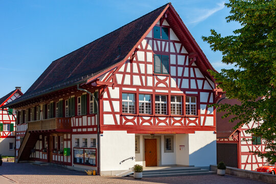 Traditional Swiss half-timbered municipality building with red wood framing under clear blue sky in Stammheim