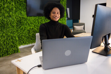 African American man smiling working black turtleneck at office with laptop living wall power cable © WavebreakMediaMicro