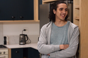Adult man leaning on kitchen cabinet, hoodie-clad, smiling and looking right by kettle, copy space © WavebreakMediaMicro