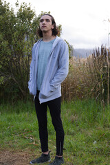 African American man standing with hands in hoodie pockets, looking upward in grassy meadow © WavebreakMediaMicro