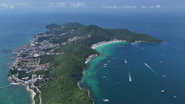 High altitude aerial view of Koh Larn island in Pattaya Thailand showcasing lush green mountains curved white sand beaches clear turquoise waters and speedboats cruising across the serene tropical sea