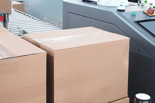 Elements of corton boxes collected in stack. Conveyor line for production of boxes. Machine cuts cardboard boxes from sheets of cardboard. Enterprise for production package.