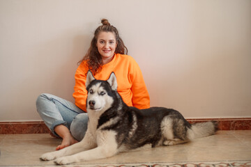 Young woman stroking Siberian husky lying on warm floor, evening that asks for nothing else, friendship without any condition. Wide shot. Concept of stroking dog as daily sign of real care © iwavephoto