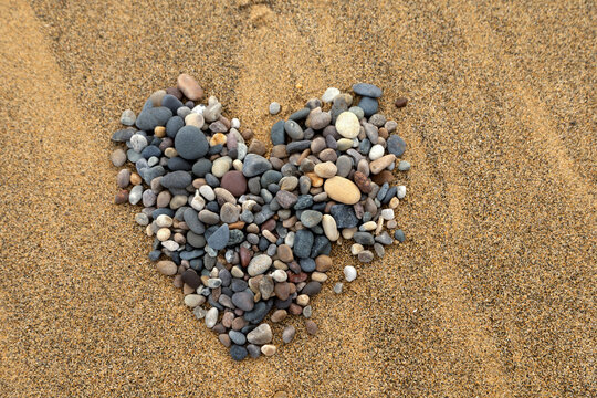 heart of stones on textured, wet, grainy sand, landscape format, copy space
