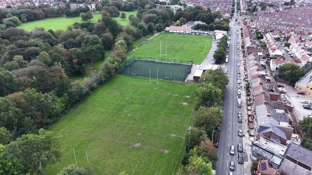 Aerial drone 4K scene showing Birkenhead Park woodland paths glowing under warm daylight with nearby housing illuminated by natural tones Birkenhead Park UK