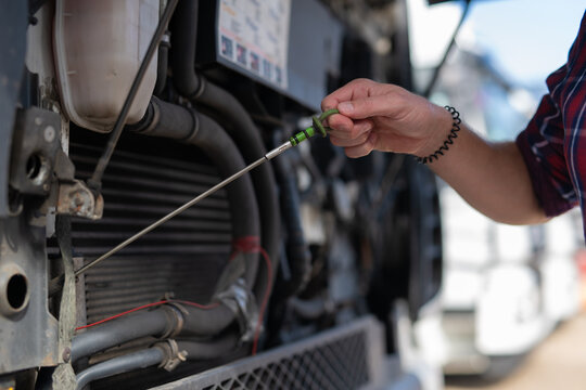 Truck driver checking engine oil level dipstick