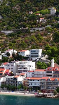 Croatia, aerial footage of a coastal village with traditional red roof houses nestled in green hills by the sea