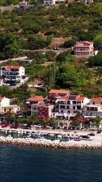 Croatia, aerial footage of a coastal village with traditional houses, marina, boats, and lush green hills by the Adriatic Sea