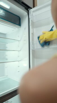 Housewife cleaning and checking the inside of a refrigerator, organizing food and maintaining kitchen hygiene as part of her everyday household routine.
