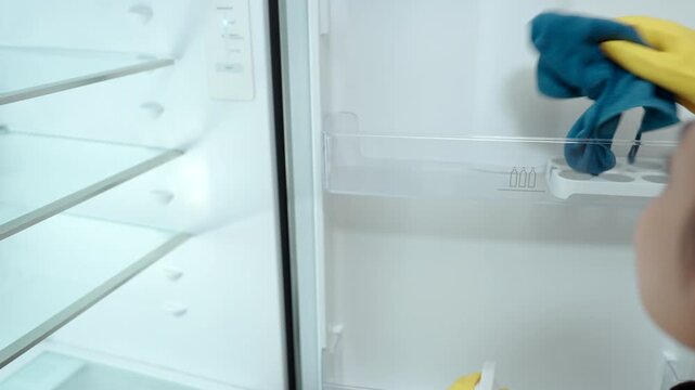 Housewife cleaning and checking the inside of a refrigerator, organizing food and maintaining kitchen hygiene as part of her everyday household routine.

