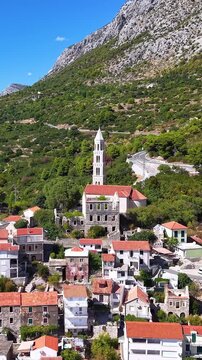 Croatia, aerial view of old church and village with red roofs nestled in mountain landscape