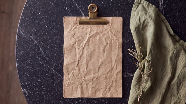 Elegant restaurant menu on kraft paper with a brass clip on a granite table