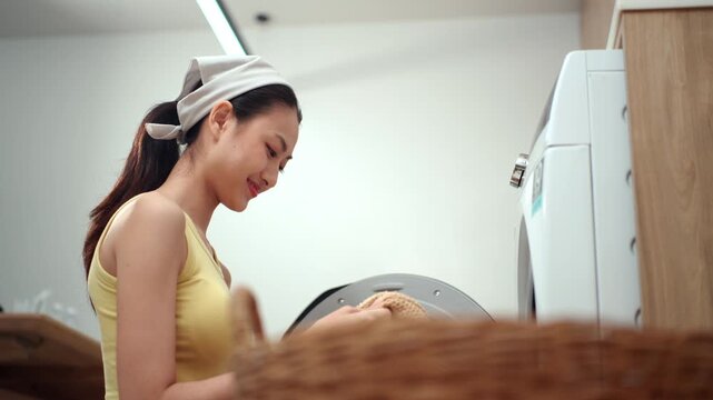 Housewife taking freshly washed clothes from a washing machine and enjoying their clean, fresh scent, highlighting laundry care, detergent, fabric softener. Household chores concept.
