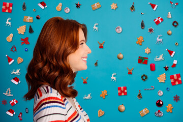 Smiling redhead woman in profile wearing striped sweater against bright blue studio background, casual portrait showing wavy hair and cheerful expression © deagreez