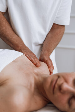 Woman receiving shoulder massage from professional therapist at spa clinic