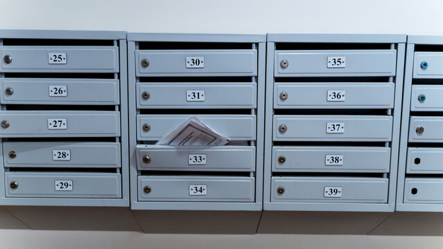 Rows of gray mailboxes line a plain wall