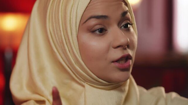 Close-up of young Muslim woman in hijab talking with family on video call
