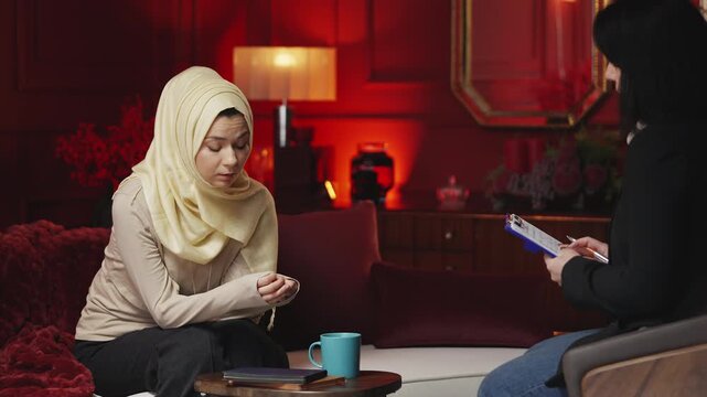 Upset young Muslim woman talking with psychiatrist, seeking emotional support