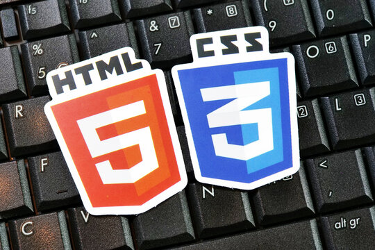 HTML5 and CSS3 logo emblems on black laptop keyboard keys, web development coding symbols, front view closeup of programming standards badges on computer hardware, technology concept