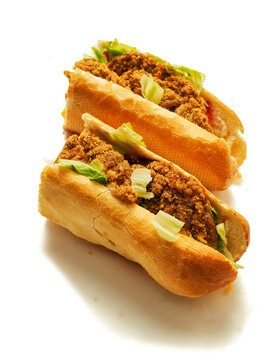 Crispy fried chicken filling in a soft, golden-brown roll bun. Fresh lettuce peeking through the savory meat. Clean white background highlights food texture and color. Perfect for fast food