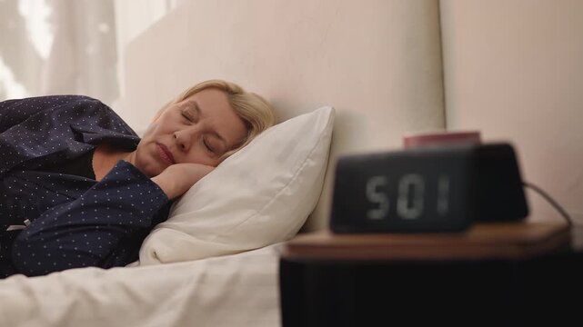 Upset middle-aged woman lies awake in bed early morning, suffering insomnia
