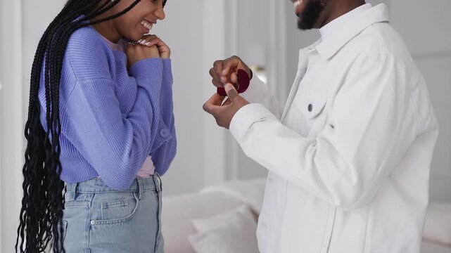 Black man presents engagement ring to happy girlfriend, proposing marriage